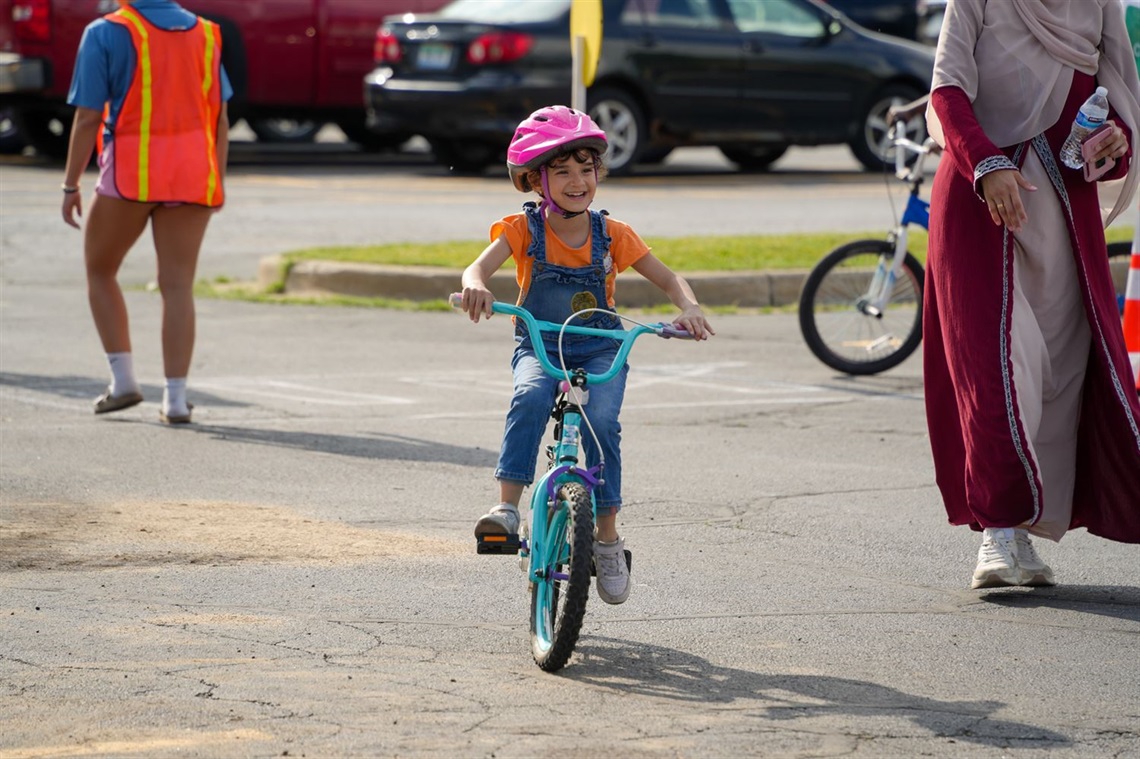 A photo of a girl smiling while riding her bike. 