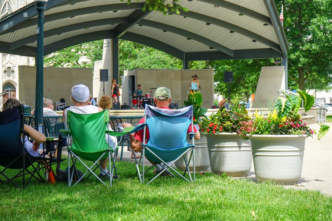 People in lawn chairs watching performance on Rotary Stage in Bronson Park in the summer. 