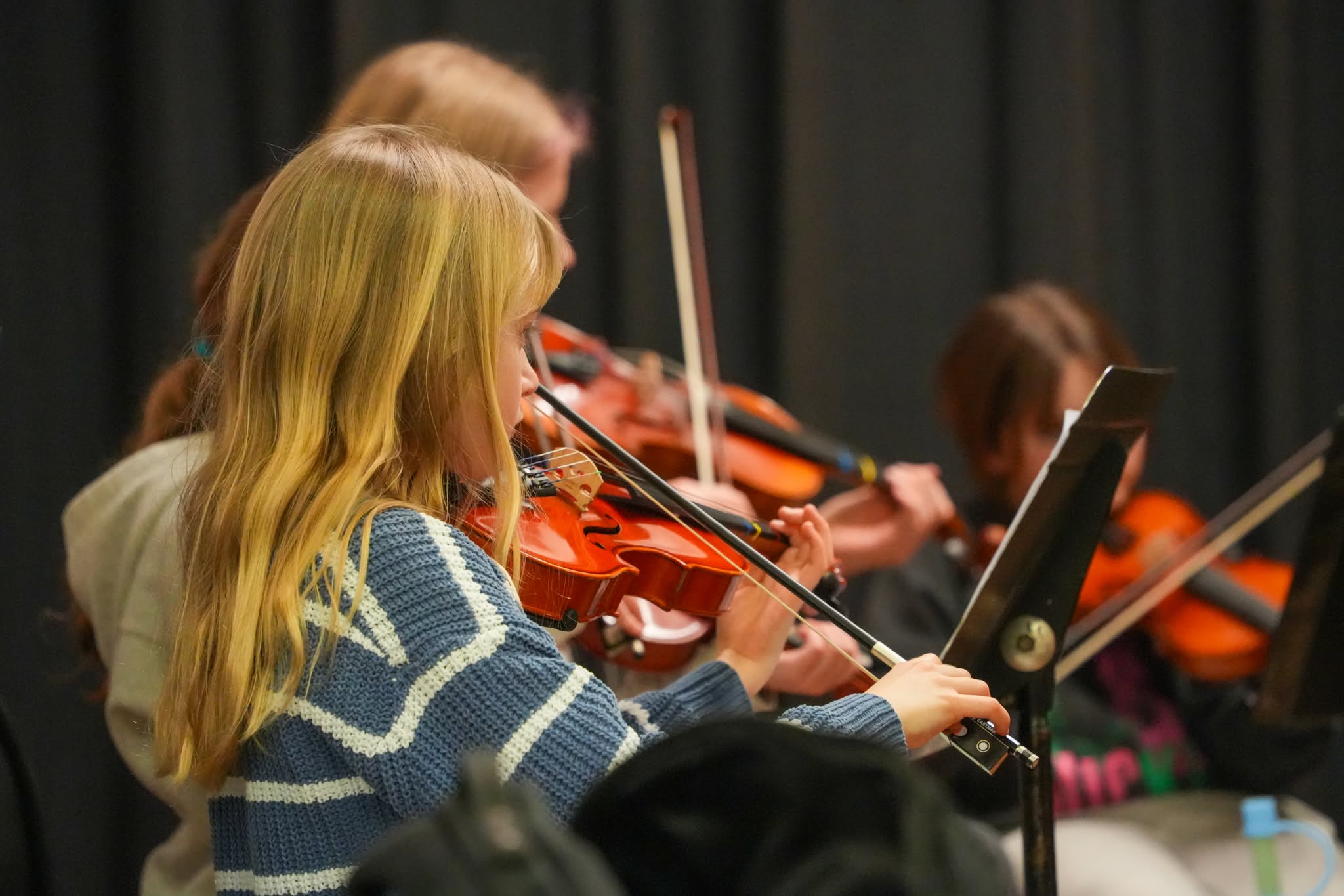 A photo of a children playing the violin and looking at their sheet music.